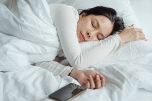 Woman sleeping in bed near smartphone
