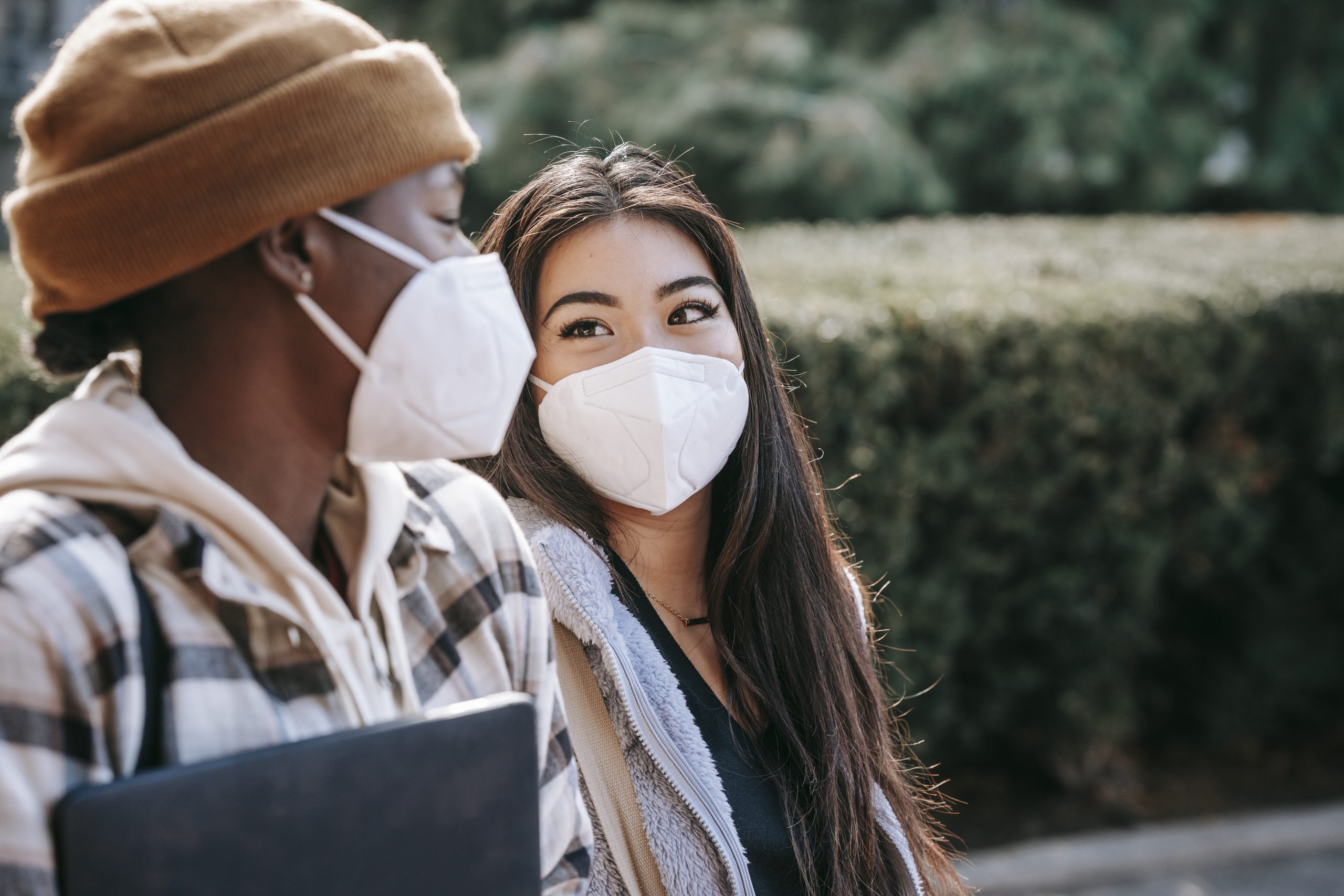 Multiracial female friends in masks strolling in street